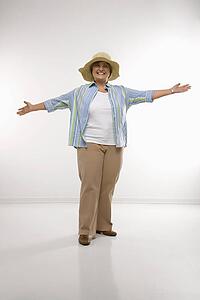 Middle aged woman wearing straw hat holding arms outstretched