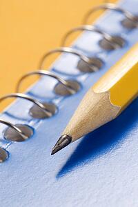 Sharp pencil placed on blue spiral bound notebook