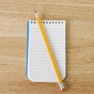 Pencil on top of open spiral bound notepad