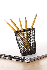 Pencils in pencil holder on top of spiral bound notebook