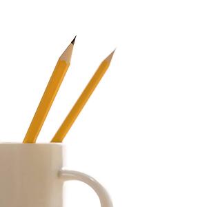 Two pencils in a coffee cup with pointed ends up.