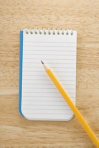 Pencil on top of open spiral bound notepad
