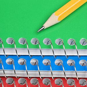 Close up of pencil on top of three spiral bound notebooks