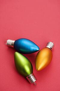 Still life of blue, green and orange Christmas ornaments on red background.