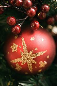 Close up of red ornament and berries on Christmas wreath.
