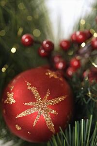 Close up of red ornament and berries on Christmas wreath.