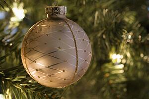 Close up of gold ornament hanging in Christmas tree.