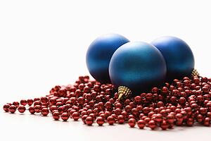 Still life of large blue Christmas ornaments and strings of red beads