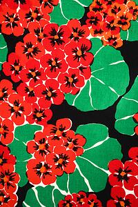 Close-up of vintage fabric with vibrant red geraniums and green leaves printed on polyester