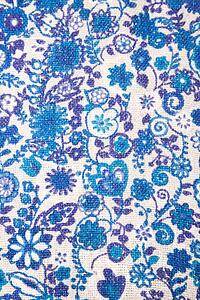 Close-up of woven vintage fabric with blue flowers and designs printed on cotton