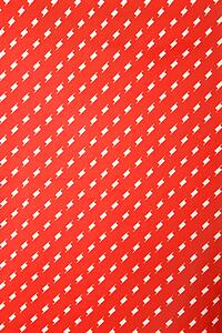 Close-up of vibrant red vintage fabric with repetitive white designs