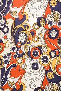 Close-up of vintage fabric with red blue and gold flowers and swirls printed on polyester