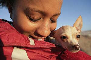 Girl with small dog wrapped in her coat