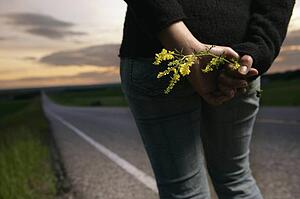 Woman standing at the side of the road with wild flowers