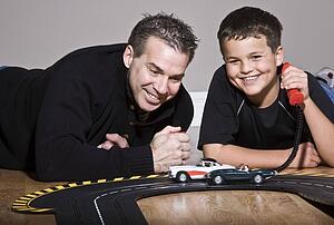 Father and son playing with toy race track