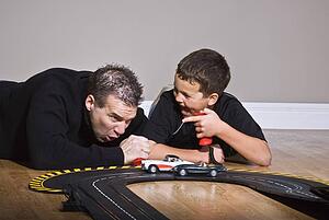 Father and son playing with race track