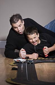 Father and son playing with race track