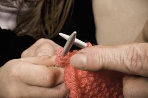 Person helping another learn to knit