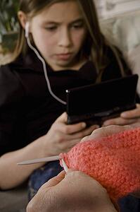 Girl with earbuds in and another person knitting