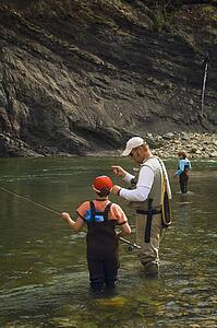 Father and sons fly fishing in mountain river 