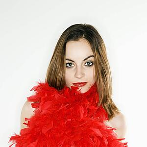 Pretty woman with red feather boa around body looking at viewer