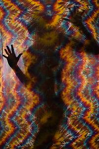 Woman silhouetted behind tye-dye fabric