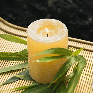 Burning candle on bamboo mat with bamboo leaves