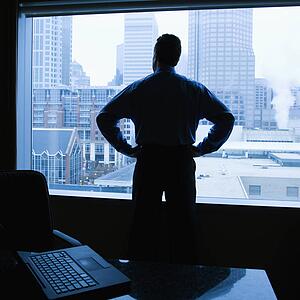 Male with hands on his hips in office with skyline in background