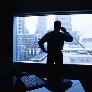 Male on phone in office with skyline in background