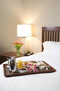 Breakfast tray laying on white bed in upscale hotel