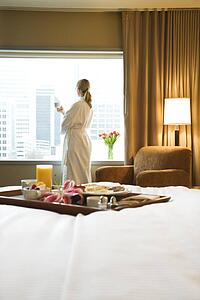 Breakfast tray on bed with mid-adult woman in background
