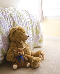 Plush brown teddy bears on bedroom floor.