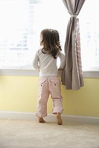 Girl standing on tip toes looking out window