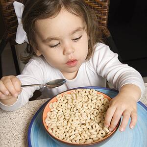 Caucasian girl eating bowl of cereal.