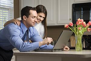 Couple in kitchen looking at laptop computer