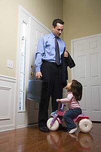 Businessman at door with briefcase with daughter looking up at him