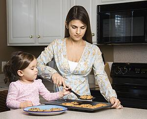 Caucasian mother and daughter with cookies.