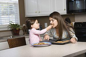 Girl feeding mother cookies