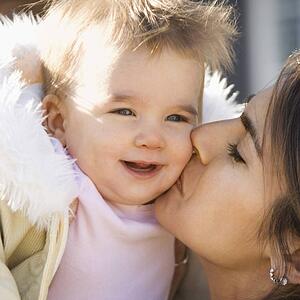 Mother holding and kissing smiling baby girl