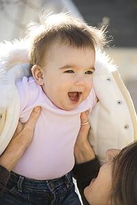 Mother holding up smiling baby girl