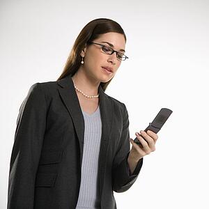 Caucasian mid adult professional business woman text messaging on cell phone.