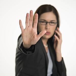 Caucasian mid adult professional business woman talking on cell phone holding hand out to stop viewer. viewer. 
