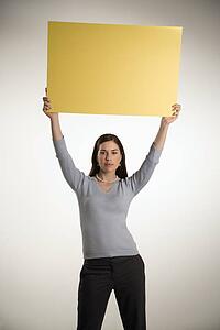 Professional business woman standing holding up blank yellow sign above her head