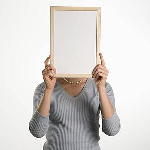 Professional business woman holding up blank dry erase board in front of her face
