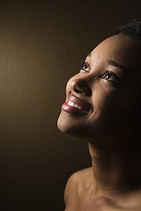 Smiling African-American young adult female looking up.