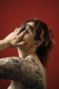 Woman with tattoos rubbing her eyes