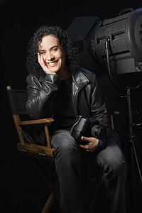 Woman smiling and holding camera in studio setting