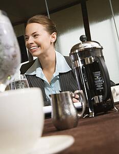 Businesswoman smiling at table with coffee and beverages