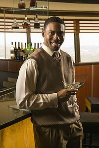 Man at bar with martini smiling at viewer