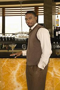 Man standing at bar with martini looking at viewer